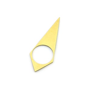 Puede incluir: Un anillo de metal de color dorado con una forma triangular puntiaguda y una abertura circular en el centro.
