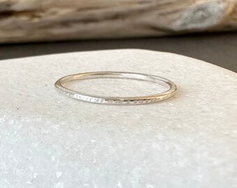 May include: A thin silver band ring with a hammered texture.