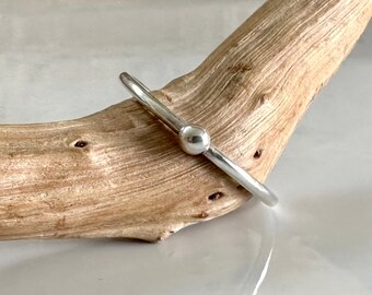 Peut inclure: Un bracelet jonc en argent avec un accent de boule ronde et lisse. Le bracelet est simple et élégant.