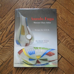 May include: Book cover featuring a colorful glass vase and plate with the title "Anzolo Fuga Murano Glass Artist" and the text "Designs for A.V.E.M."