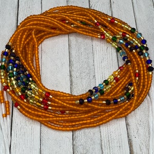 May include: A waist bead necklace made of orange glass beads with accents of blue, green, gold, and red glass beads.