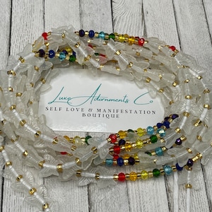 Puede incluir: Cuentas de cintura blancas con dijes de mariposa y cuentas de acento coloridas. Las cuentas de la cintura est&aacute;n ensartadas en un cord&oacute;n blanco y presentan detalles dorados. La imagen incluye una tarjeta con el texto "Luxe Adornments Co. SELF LOVE & MANIFESTATION BOUTIQUE."