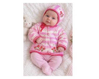 May include: A pink and white striped knit cardigan with a button-front closure and floral embroidery at the hem, paired with a matching knit bonnet featuring a red trim and floral accents, and solid light pink knit pants with integrated feet.