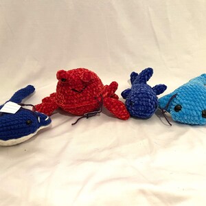 May include: Four crocheted stuffed animals: a red crab, a blue stingray, a blue fish, and a blue stingray.