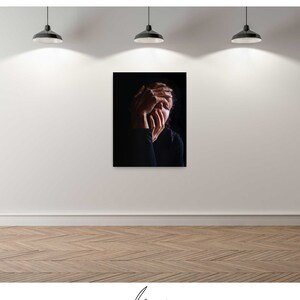 May include: A black and white photograph of a person with their hands covering their face. The person is wearing a black shirt and is in a dark room.