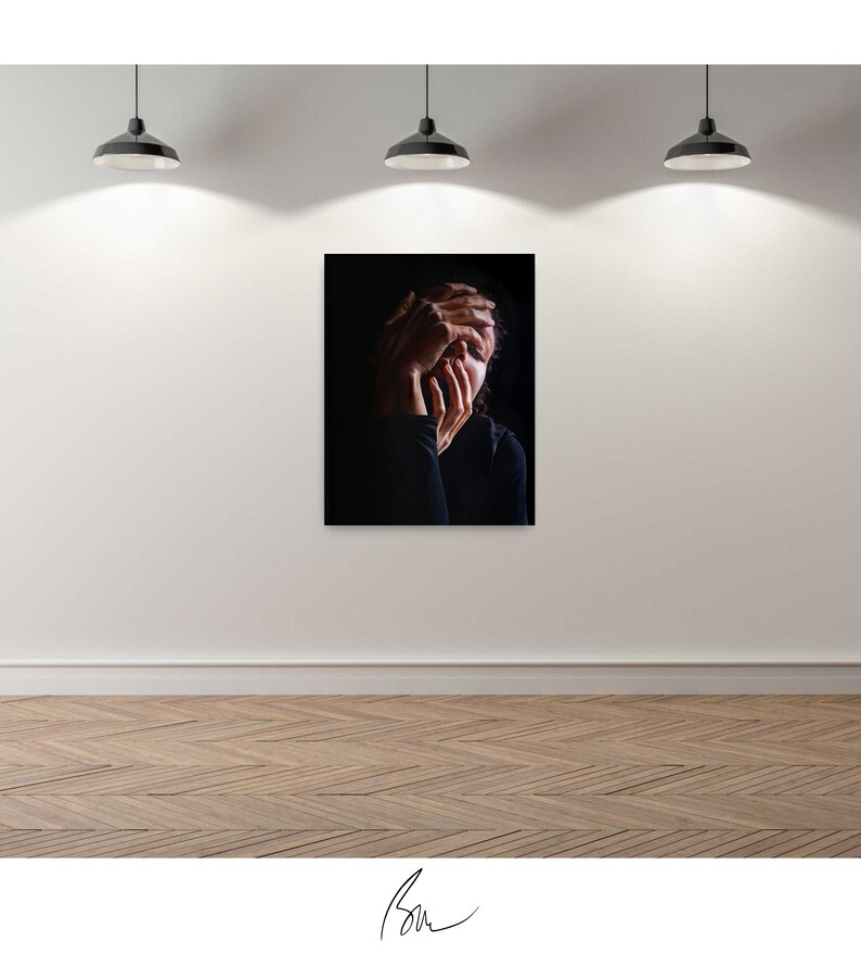May include: A black and white photograph of a person with their hands covering their face. The person is wearing a black shirt and is in a dark room.