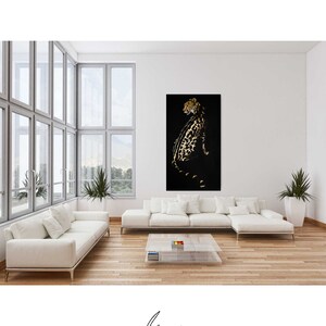 Op de afbeelding: Een zwart-gouden cheeta-print kunstprint in een moderne woonkamer met een witte bank en een glazen salontafel.