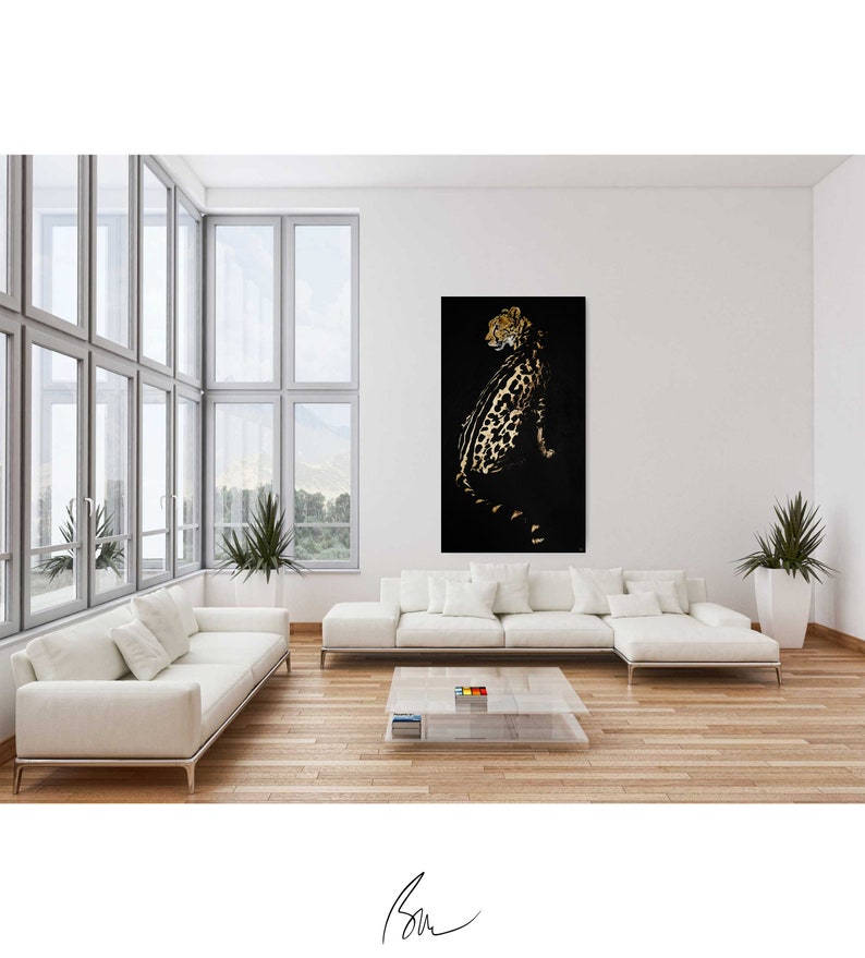 Op de afbeelding: Een zwart-gouden cheeta-print kunstprint in een moderne woonkamer met een witte bank en een glazen salontafel.