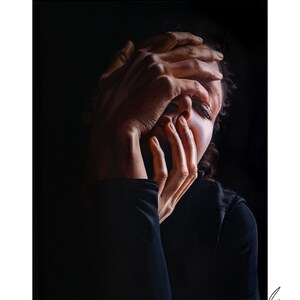 May include: A person with dark hair covers their face with their hands. The person is wearing a dark shirt and is lit from the side, creating a dramatic effect.