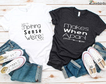 Puede incluir: Dos camisetas con un diseño de pareja a juego. La camiseta blanca dice "Nothing Sense We're" y la camiseta gris oscuro dice "Makes When Apart" con una flecha.