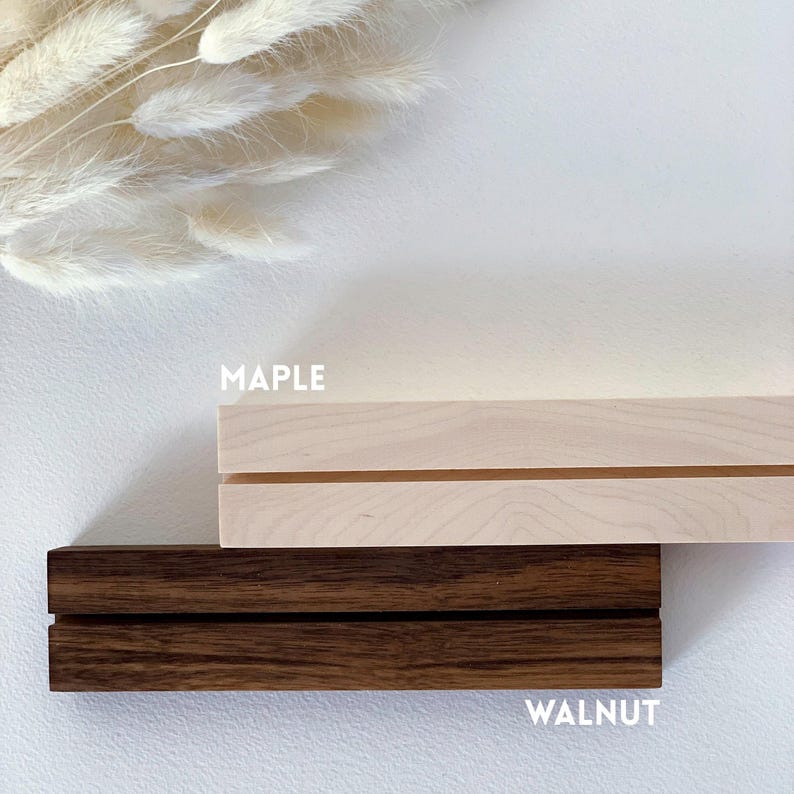 May include: Two wooden display stands, one in maple and one in walnut. The maple stand is light brown and the walnut stand is dark brown. Both stands have a groove for holding a picture or other item.