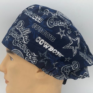 Könnte beinhalten: Eine blaue und weiße OP-Mütze mit einem Dallas Cowboys-Muster. Die Mütze zeigt das Logo des Teams, die Worte "Dallas Cowboys" und Sterne.