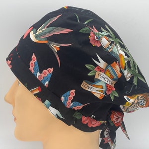 Könnte beinhalten: Schwarze OP-Mütze mit einem farbenfrohen Tattoo-inspirierten Druck mit Vögeln, Blumen und den Worten "Forever Love".