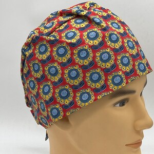 Könnte beinhalten: Rote OP-Mütze mit einem blauen und gelben Blumenmuster.