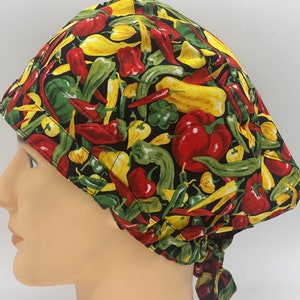 Könnte beinhalten: Eine schwarze OP-Mütze mit einem bunten Muster aus roten, gelben und grünen Paprikaschoten. Die Mütze hat einen Bindegurt an der Rückseite.