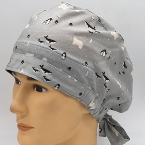 Könnte beinhalten: Graue OP-Mütze mit einem weißen und schwarzen Druck von arktischen Tieren. Die Mütze hat einen Bindfaden an der Rückseite.