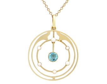 May include: A gold pendant necklace with a circular design featuring a blue gemstone surrounded by six white pearls. The pendant is suspended from a delicate gold chain.