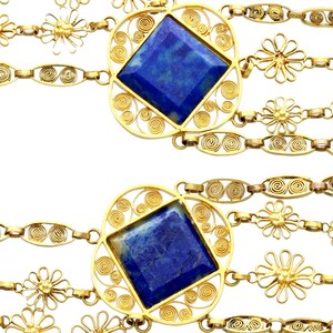 May include: A gold chain necklace with multiple strands featuring blue gemstone pendants and flower-shaped charms.