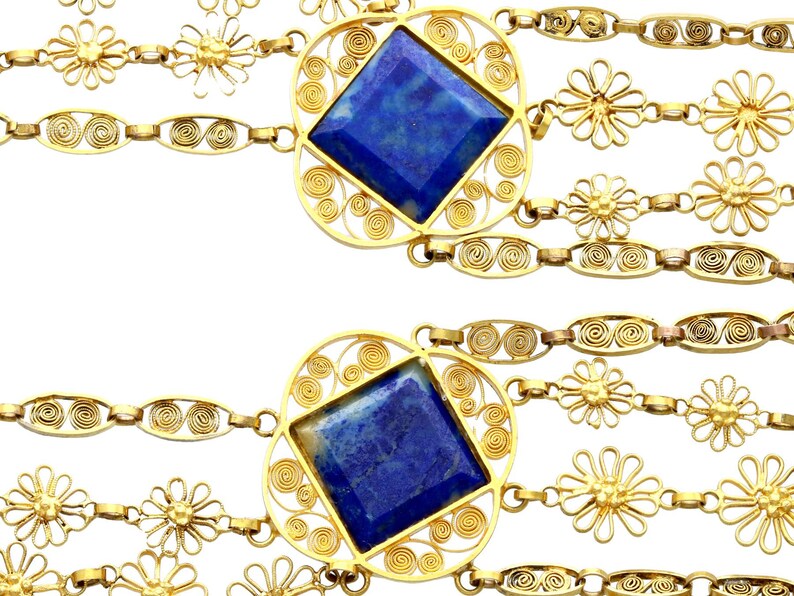 May include: A gold chain necklace with multiple strands featuring blue gemstone pendants and flower-shaped charms.
