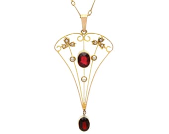 May include: A gold pendant featuring a central oval red garnet stone surrounded by small white pearls. The openwork metal frame has a fan-like shape with delicate wire detailing, additional pearl accents, and a dangling oval red garnet stone.