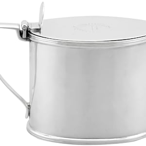 Puede incluir: Un azucarero ovalado de plata con tapa con bisagras y asa. El bol tiene una superficie lisa y pulida.