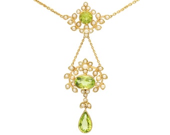 Op de afbeelding: Een gouden ketting met een parel- en groene edelsteenhanger. De hanger heeft een druppelvormige edelsteen en een cluster van kleinere edelstenen.