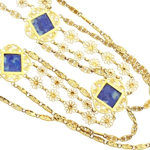 May include: A multi-strand gold necklace with blue stone accents. The necklace features a delicate floral design and square-shaped stones.