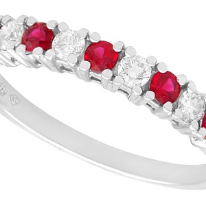 May include: A silver band ring with alternating red rubies and clear diamonds. The ring has a polished finish.