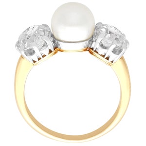 May include: A gold ring with a large pearl and two smaller diamonds. The ring is set in a three-stone design.