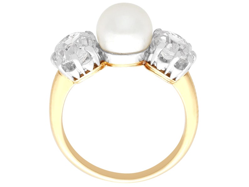 May include: A gold ring with a large pearl and two smaller diamonds. The ring is set in a three-stone design.