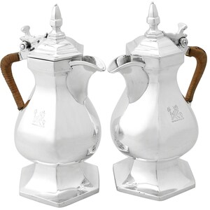 May include: A pair of silver coffee pots with brown wooden handles and lids. The pots have a hexagonal base and a rounded body.