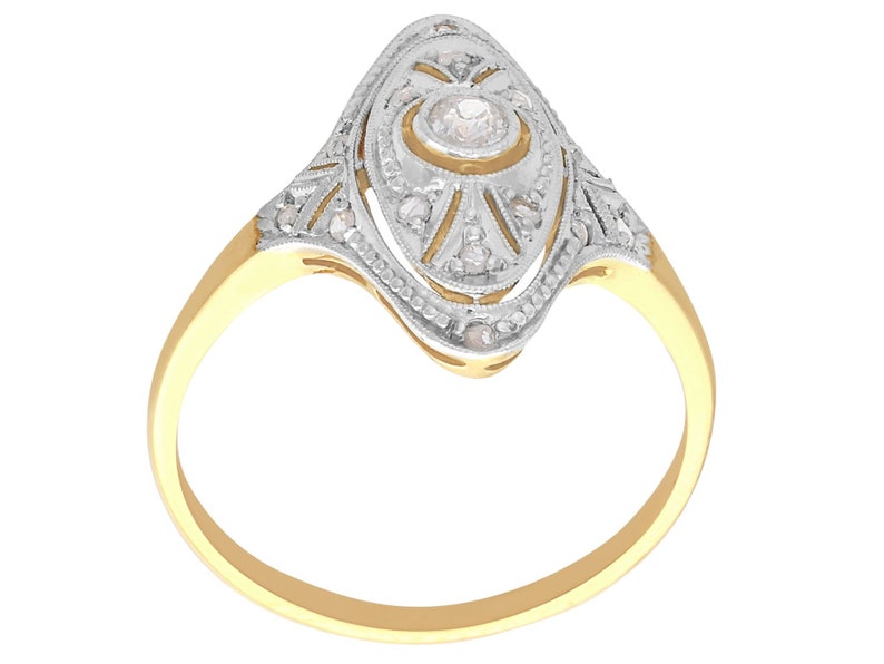 May include: A gold ring with a diamond set in a delicate, oval-shaped design. The ring is adorned with intricate details and a sparkling center stone.