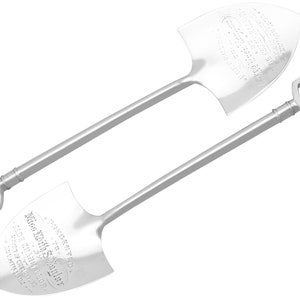 Puede incluir: Dos palas ceremoniales de plata con texto grabado. Las palas están diseñadas para parecer versiones en miniatura de palas tradicionales.