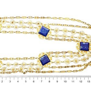 May include: A gold chain necklace with five strands featuring a delicate floral design and square lapis lazuli stones. The necklace is measured on a ruler in inches.