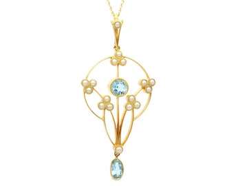 May include: A delicate gold pendant necklace with a teardrop-shaped aquamarine gemstone and a cluster of pearls. The pendant features a floral design with a circular frame.