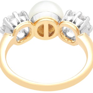 May include: A gold ring with a pearl and two diamonds. The ring is set in a three-prong setting.