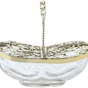 Pode incluir: Uma cesta de fruta de prata e vidro com uma alça decorativa. A cesta é oval e tem uma tigela de vidro transparente com um design de vidro cortado. A alça de prata é torcida e tem um design floral.