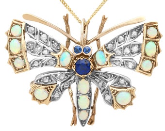 Könnte beinhalten: Ein goldener Schmetterlingsanhänger mit Opal- und Saphir-Edelsteinen. Die Flügel des Schmetterlings sind mit einem filigranen Muster aus Diamanten verziert.