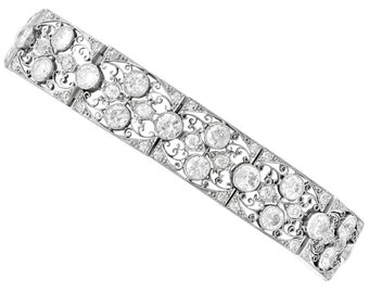 May include: A silver bracelet with a delicate filigree design and round, clear stones.