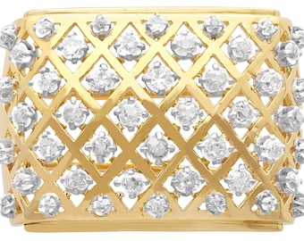 Op de afbeelding: Een gouden ring met een ontwerp dat is bezet met diamanten. De diamanten zijn in een rasterpatroon gezet, wat een geometrische uitstraling creëert. De ring is gemaakt van 14 karaats goud en is een prachtig sieraad.