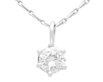 Op de afbeelding: Een zilveren ketting met een enkele, ronde, heldere diamant hanger.