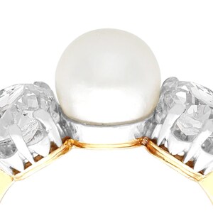 May include: A gold ring with a large white pearl in the center and two smaller diamonds on either side.