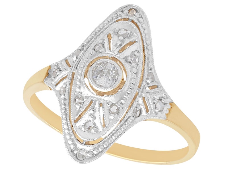 May include: A vintage-style gold ring with a delicate diamond design. The ring features a central diamond surrounded by smaller diamonds in a geometric pattern.