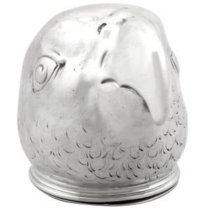 Könnte beinhalten: Ein silberfarbener, vogelförmiger Behälter mit detailliertem Design. Der Behälter hat einen abgerundeten Körper mit einem Sockel und einem detaillierten Vogelkopf, einschließlich Auge und Schnabel. Die Oberfläche hat ein strukturiertes, gefiedertes Muster.