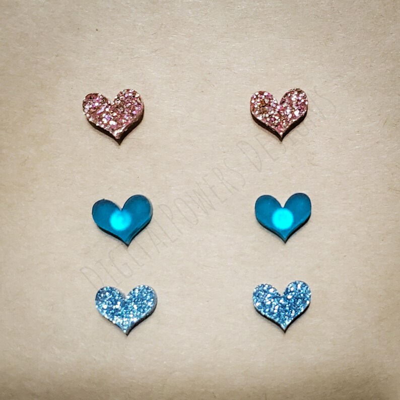 May include: Six heart-shaped earrings, two pink glitter, two blue glitter, and two blue with a clear centre.