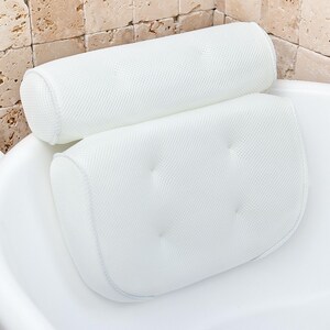 Bath pillow and bathtub tray set, the pillow on its own: white air mesh with a roll headrest and a tufted lower panel, seated on the rim of a white tub.
