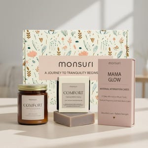 May include: A gift set with a candle, soap, and affirmation cards. The candle jar and soap box are labeled "Comfort." The affirmation cards are labeled "Mama Glow." The box has a floral design and the text "A Journey to Tranquility Begins."