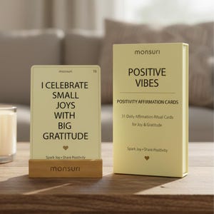 May include: A set of "Positive Vibes" affirmation cards with a wooden card holder. The cards are light yellow with black text that reads "I Celebrate Small Joys With Big Gratitude." The box reads "Positive Vibes" and "Positivity Affirmation Cards."