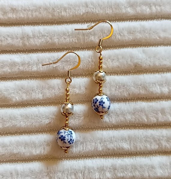 Gold-tone stainless steel drop earrings with gold beads and blue flowers