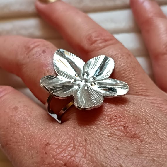 Adjustable silver or gold-tone stainless steel ring with a large flower.